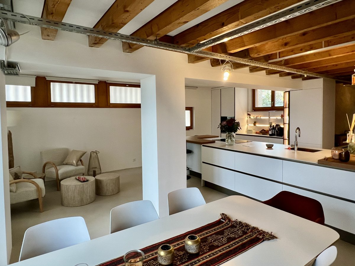 Vue 3D de la proposition d'Aménagement pour la cuisine. Meubles blanc et plan de travail imitation bois. Coin repas sur lîlot et coin café sous la fenêtre. 